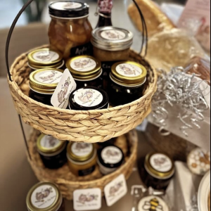 a photo of a two tier basket of assorted jars of jams, jellies, preserves, canned products, all from Honey + Fig Farm.