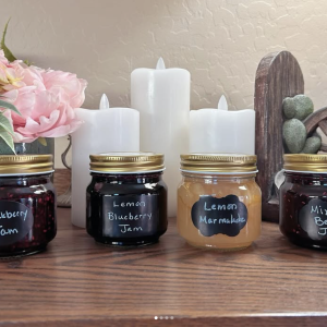 photo of four jars of products in a southwestern decorated background: blackberry jam, lemon blueberry jam, lemon marmalade, and mixed berry jam.